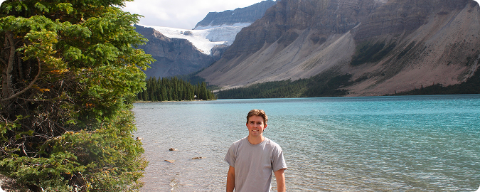 Wilson standing by a lake in the mountains